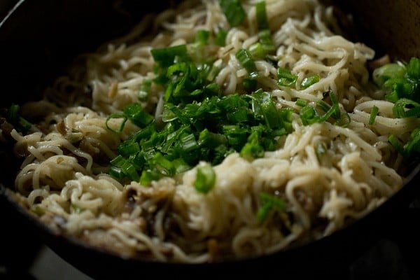 garnishing spring onions on mushroom noodles 