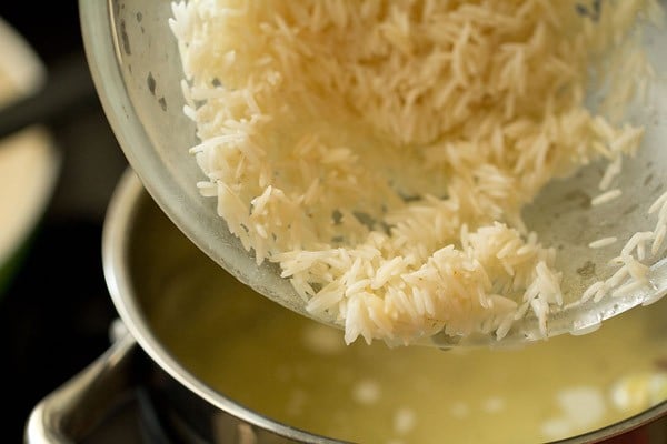 adding soaked rice to the hot water in the pan