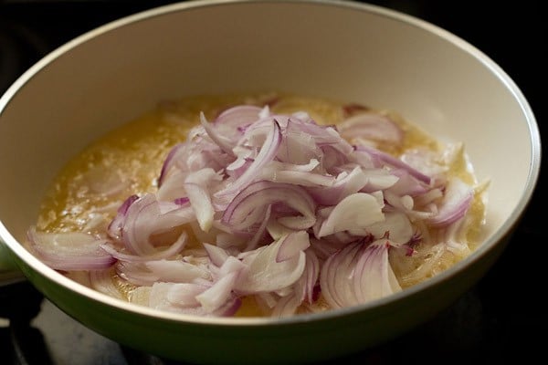 sliced red onions in a pan over simmering oil