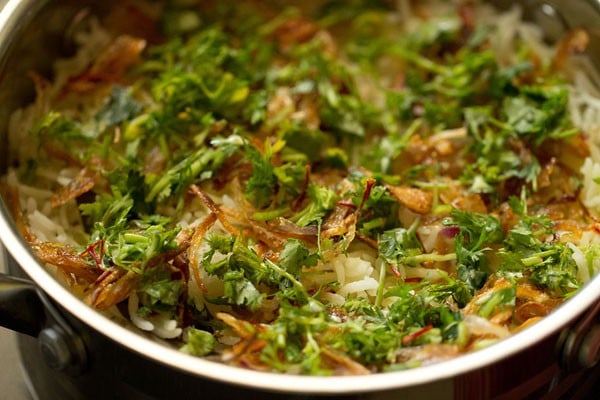 coriander and mint leaves sprinkled on the fried onions layer