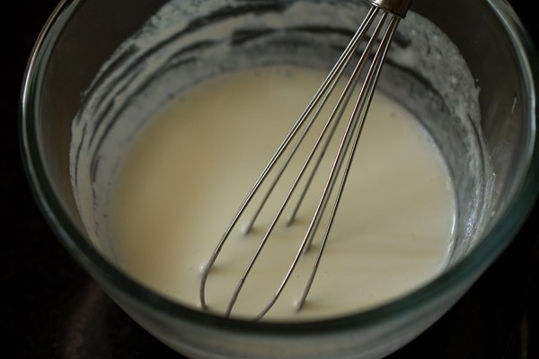 curd being whisked with a wired whisk in a glass bowl