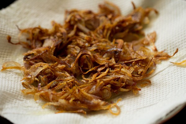 fried golden caramelized onions on kitchen paper towels to make paneer biryani