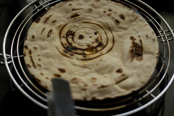 the swirl pattern on the roti is still visible, but the rest of the roti also has some bits of char.