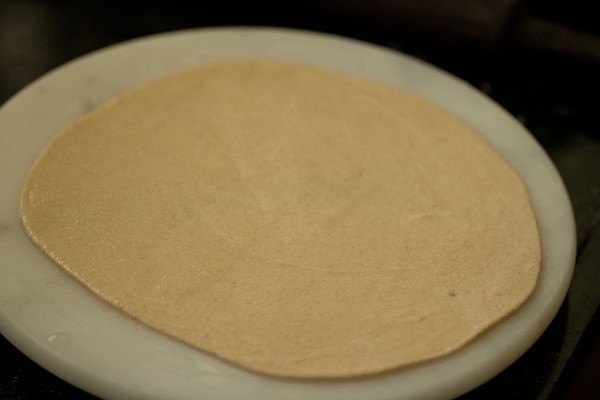 rolling roti - showing a side angle of thickness of the roti and demonstrating water across the top.