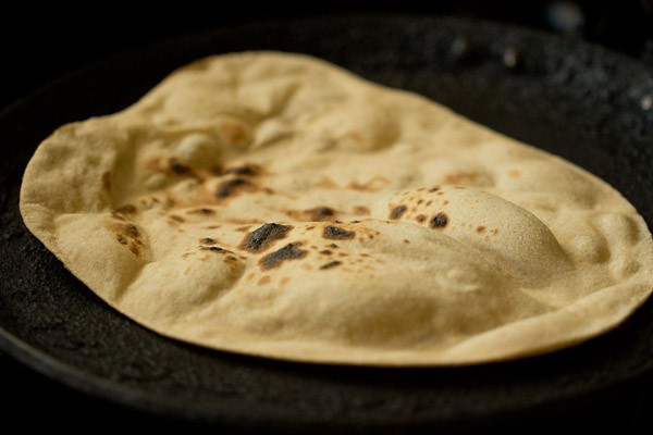 tandoori roti, has large air-pockets, and the top is now lightly blistered with char spots from the flame.
