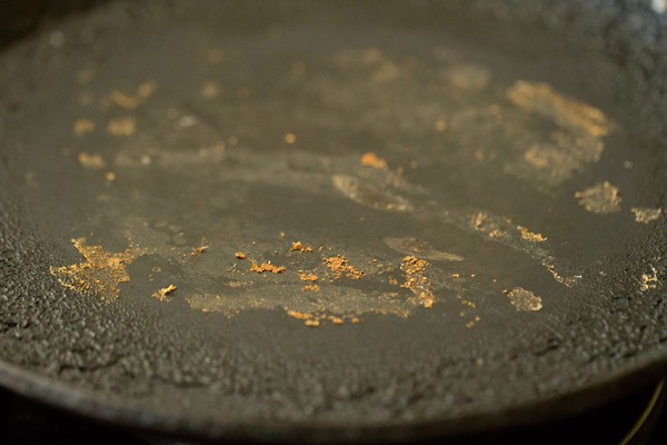 showing the dough that has stuck to the tawa after cooking a roti.