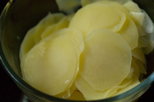 adding the drained potato slices to a mixing bowl.