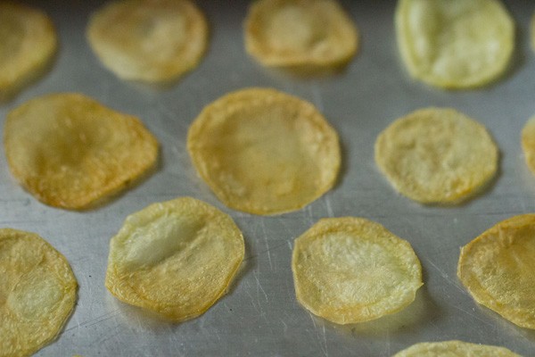 baked potato chips on the sheet have become lightly golden and apparently crispy.