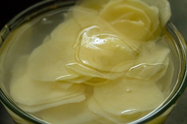 sliced potatoes soaking in salt water for potato wafers recipe.