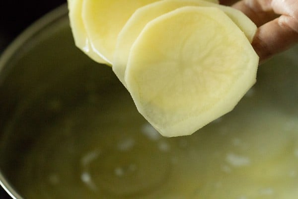 adding potatoes to the boiling water for baked potato chips recipe.