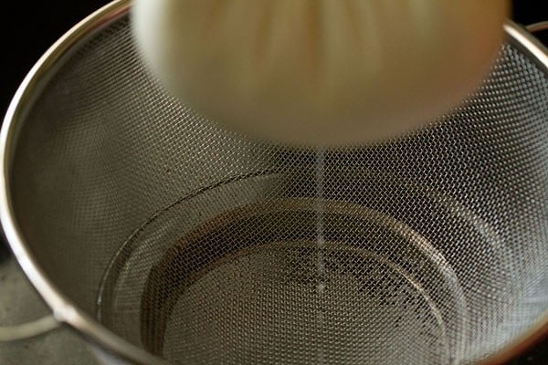 pressing the muslin to release whey from curd