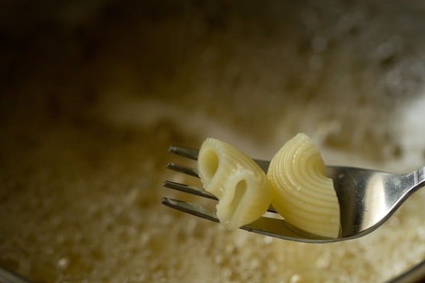 fork holding 2 pieces of cooked pasta.