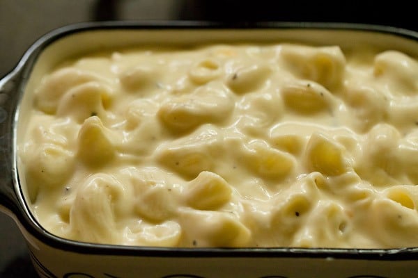 adding macaroni and cheese to prepared casserole dish. 