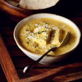 methi malai paneer garnished with grated paneer and served in a bowl with a side of roti.