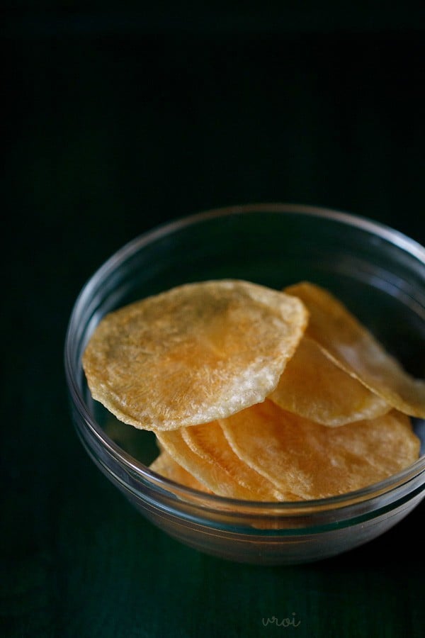 oven baked potato chips or potato wafers in a glass jar on a black table. 