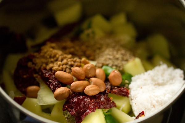 chopped mangoes, dried red chilies, green chili, sesame seeds, peanuts, grated coconut and powdered jaggery in a grinder jar. 