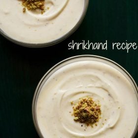 top shot of shrikhand with chopped pistachios on a dark green serving tray with a text layover