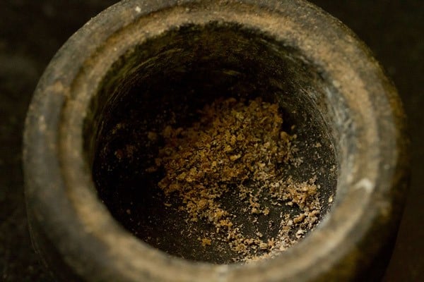 cardamom crushed in the base of a mortar for shrikhand recipe
