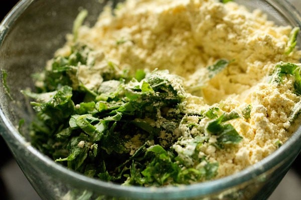 finely chopped methi leaves and gram flour added to a mixing bowl for making methi muthia for undhiyu recipe.