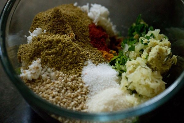 sesame seeds, crushed ginger, crushed garlic, crushed green chilies, spice powders, lemon juice, sugar and salt added to bowl for undhiyu recipe.