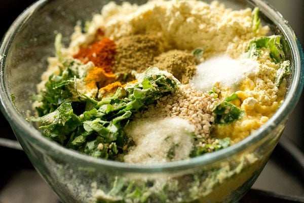 baking soda, spice powders, oil, sugar, salt and lemon juice added to bowl for making methi muthia for undhiyu recipe.