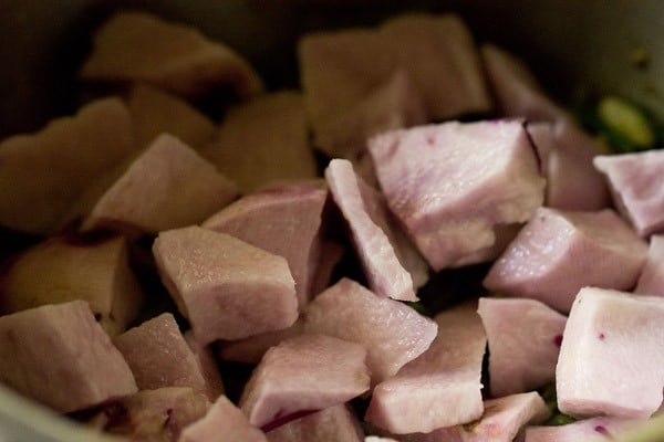 layer of chopped purple yam spread over beans layer for making undhiyu. 