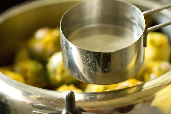 adding water on the sides for cooking undhiyu. 