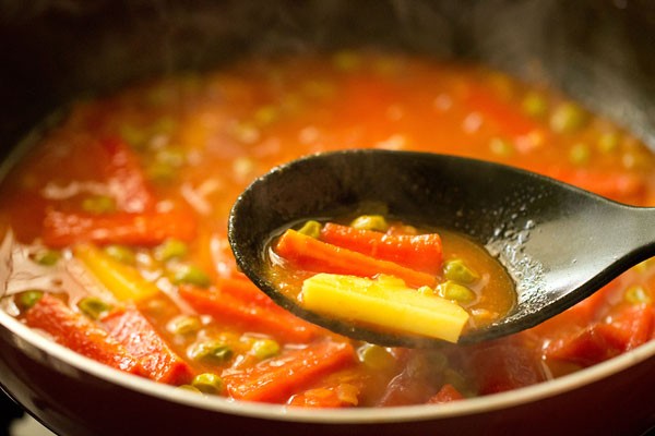 cooked vegetables in a black spoon