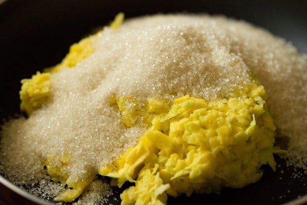 grated raw mangoes and sugar added in a pan. 