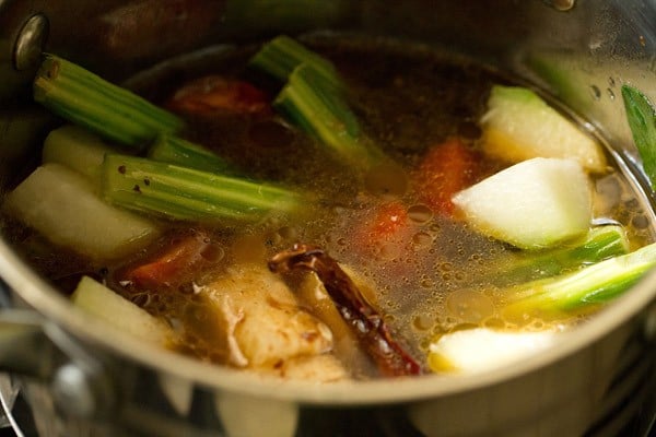 adding water to the vegetables in pan