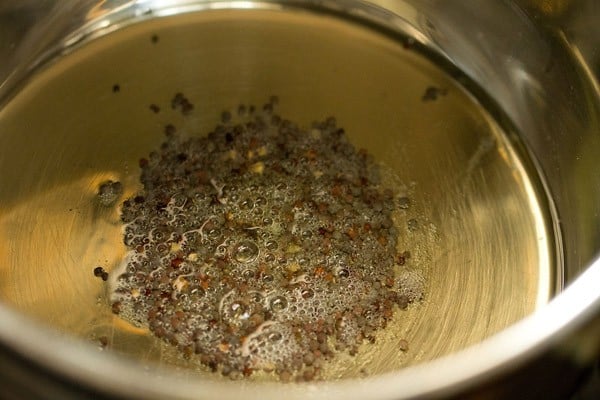 crackling mustard seeds in hot sesame oil in pan