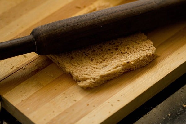 flattening a bread slice with a rolling pin. 