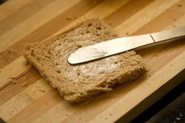spreading butter on flattened bread slice. 
