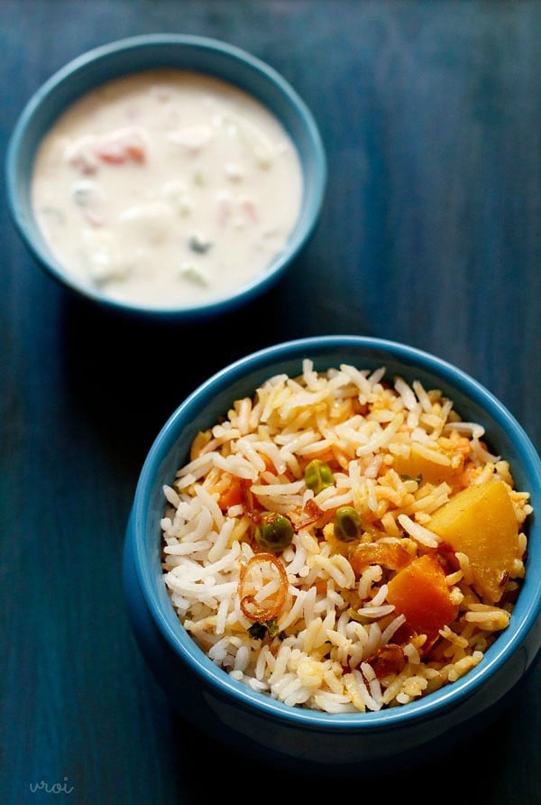 Bombay biryani served on a bowl with a side of raita