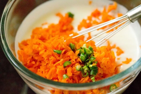 adding grated carrots and chillies to curd
