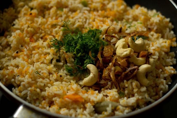 added coriander leaves and onions, cashews, raisins mixture to carrot rice