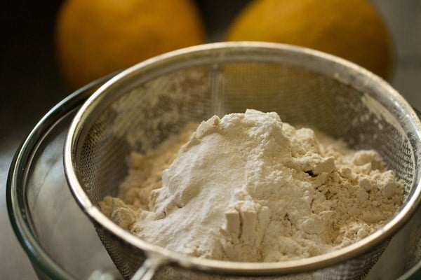 flour and leavening being sifted for making eggless mango cake recipe