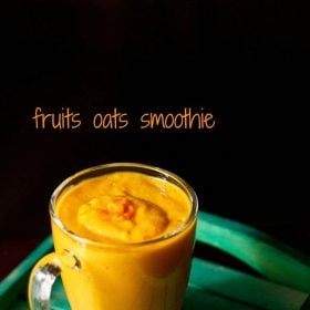 bright orange colored fruit and oatmeal smoothie in a glass mug on a green table.