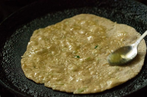 applying ghee on flipped side of lauki paratha