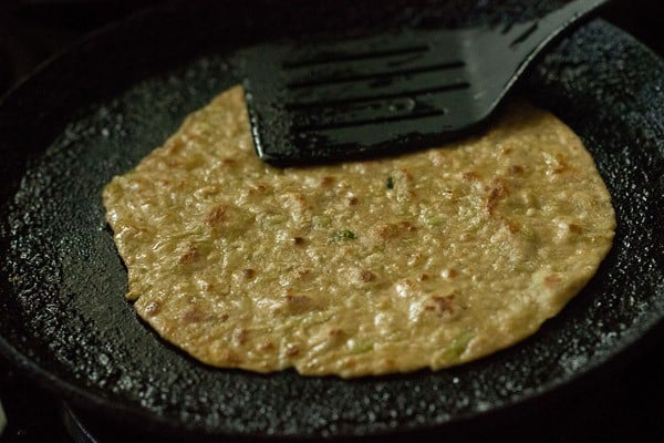 pressing lauki paratha edges with a spatula