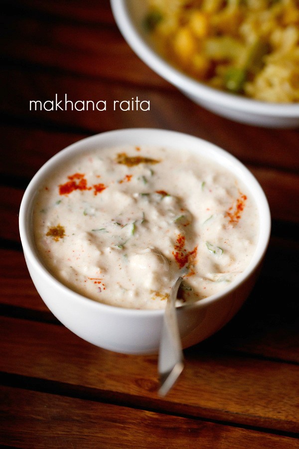 makhana raita served in a white bowl with a spoon in it and text layover.