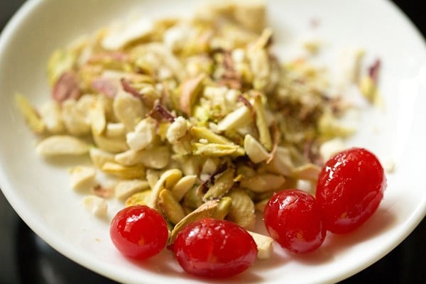 sliced dry fruits and glazed cherries on a plate for mango mastani. 