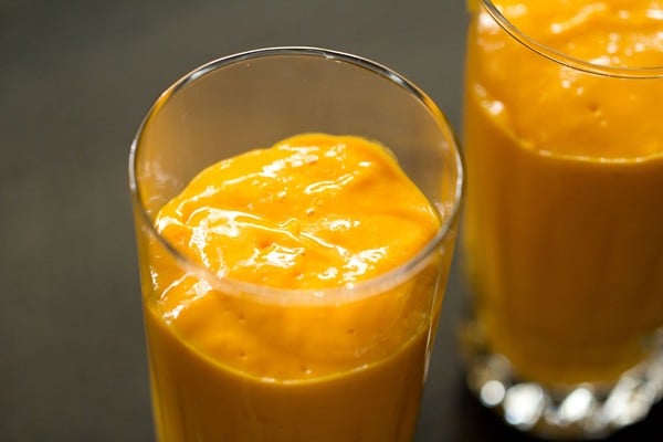 thick mango milkshake poured in glasses. 