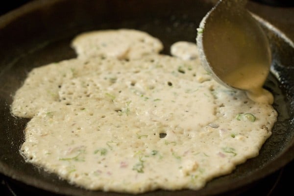 oats dosa batter on a pan with the gaps filled