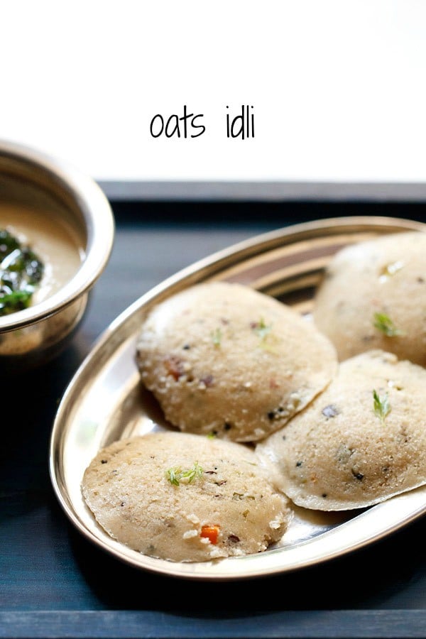 Top shot of four round oats idli arranged on silver plate with coconut chutney in a silver bowl.