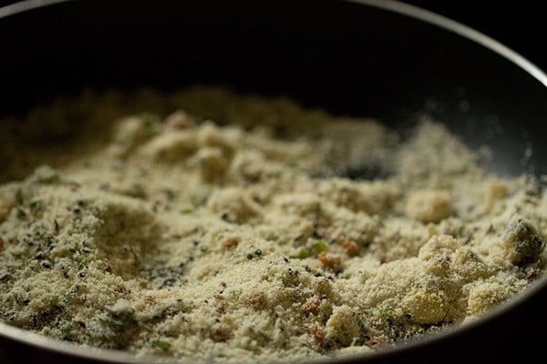 Closeup shot of sooji sautéing in black skillet.