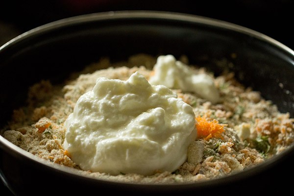 Curd added to oats idli in black bowl.