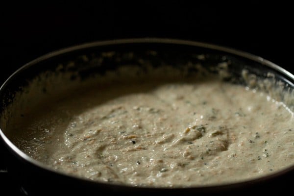 Oats idli batter in black skillet.