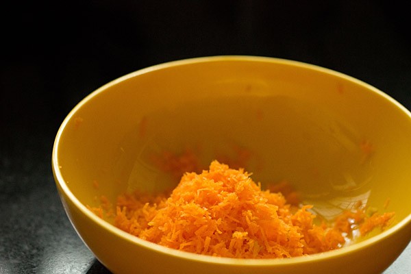 Grated carrot in small yellow bowl.