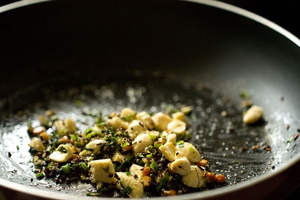 Ginger, nut, and seasoning mixture sautéing in black skillet.